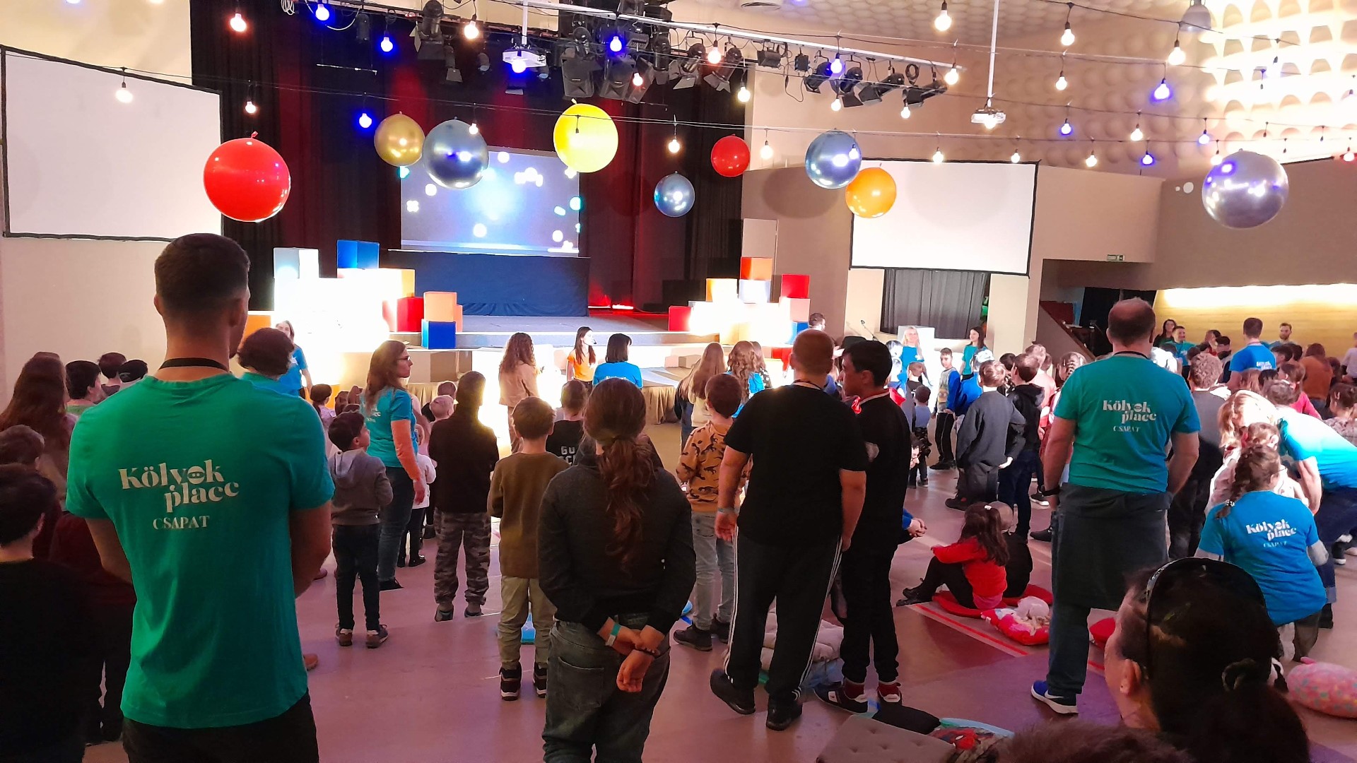 Színházterem – gyerekprogram, izgatott gyerekek a színpad előtt